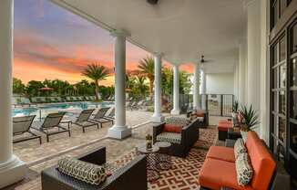 Covered veranda seating by the pool at Palm Ranch Apartments in Davie, FL