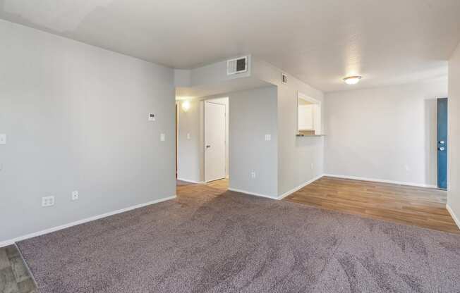 an empty living room with a wood floor and white walls
