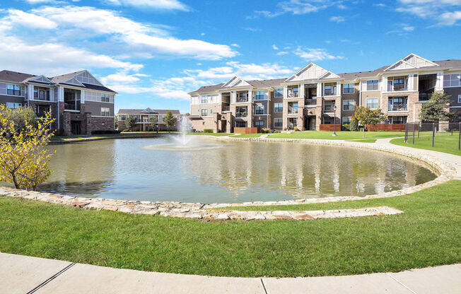 pond with fountain with apartment buildings in the background