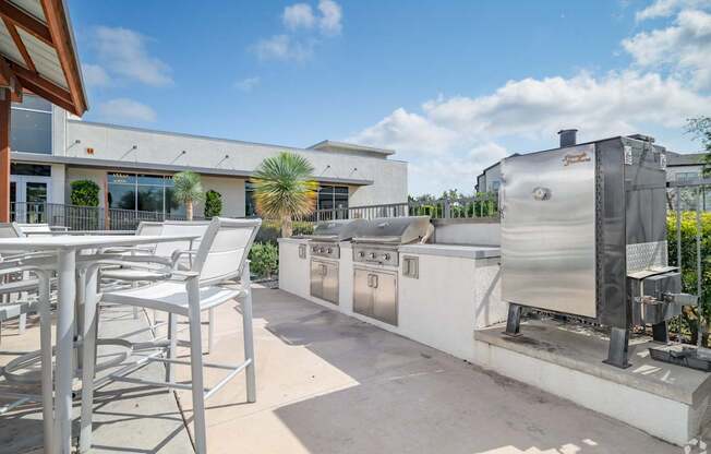 A patio with a table and chairs and a BBQ grill.