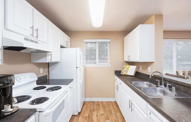 a kitchen with white appliances and counters and a sink