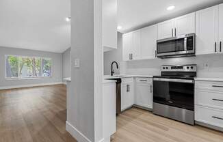 A kitchen with white cabinets and a wooden floor.