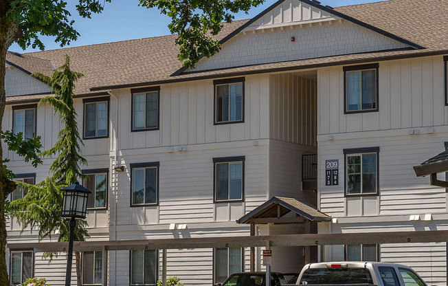 A large white building with a brown roof and a truck parked in front at Riverplace Apartment Homes, Independence, OR