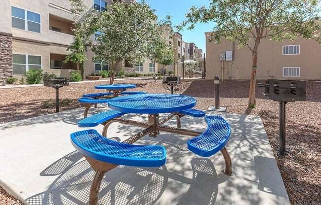 an outdoor picnic area with blue picnic tables and benches