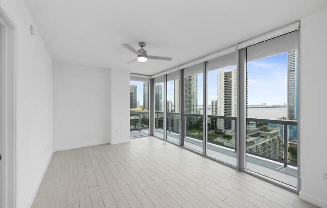 an empty living room with a ceiling fan and a view of the city