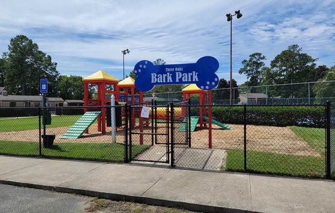 a park with a playground and a blue sign that reads bark park