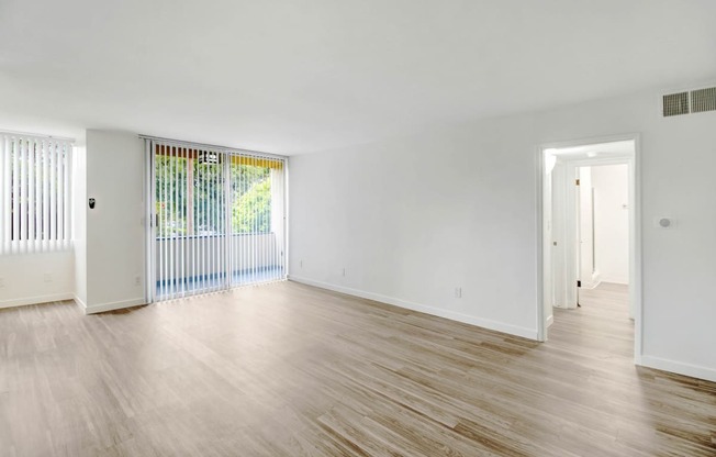 the living room and dining room of an empty house with wood floors and white walls