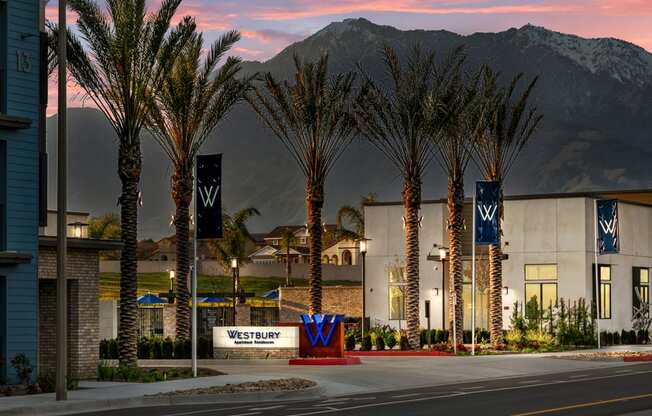 a city street with palm trees and a building with mountains in the backgroundat Westbury Apartments, Rancho Cucamonga, California 