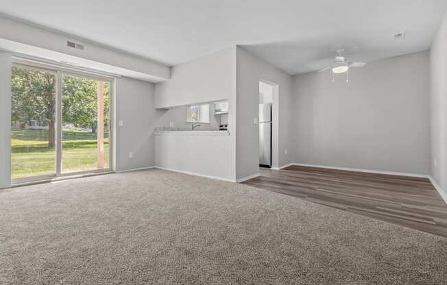 an empty living room with a large window and a kitchen