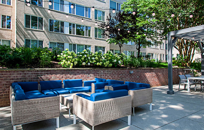 a patio with blue couches and chairs in front of a building
