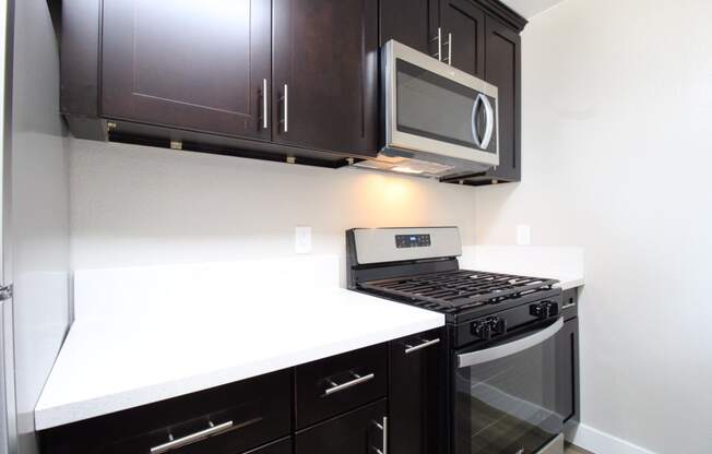 a kitchen with a stove and microwave and dark cabinets