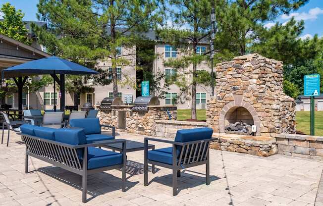 A patio with a stone fireplace and two chairs.