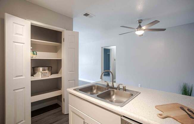 a kitchen with a sink and a ceiling fan