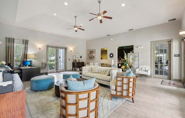 A spacious living room with a white couch, a blue ottoman, and a wooden coffee table.