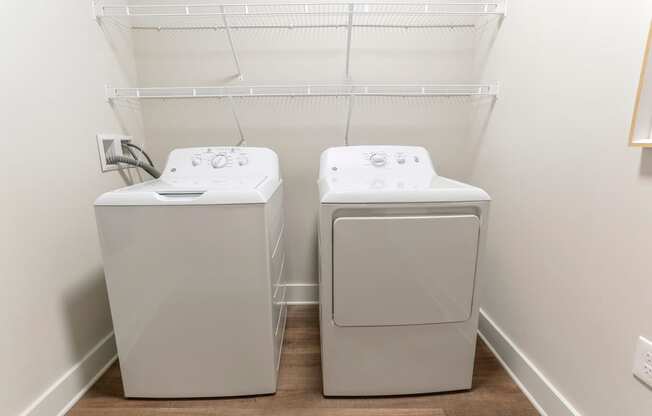 a washer and dryer in a room with a white wall and wood floor