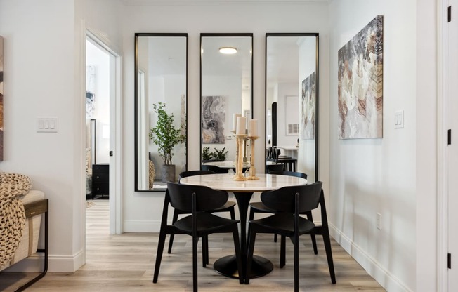 a small dining area with a round table and four black chairs