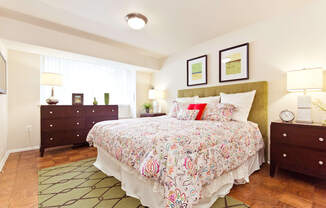 A bedroom with a floral bedspread and a green headboard.