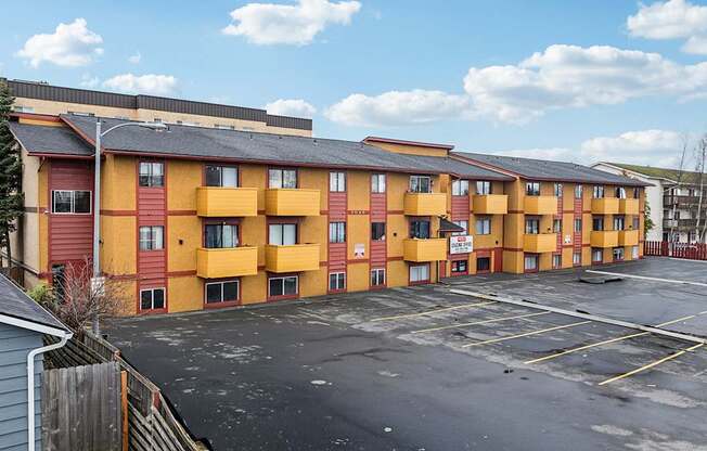 A parking lot in front of a row of apartment buildings.
