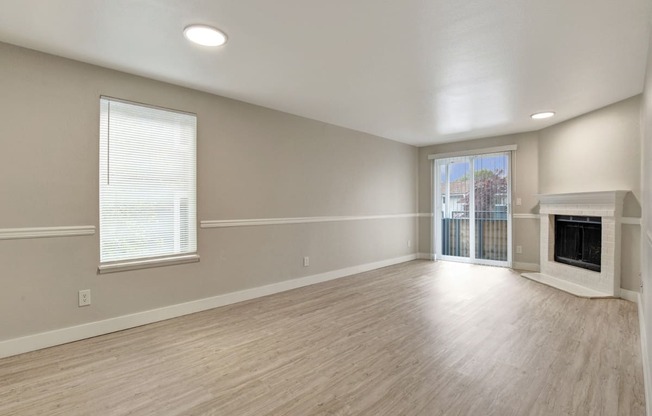 an empty living room with a fireplace and a sliding glass door at 2000 Lake Washington Apartments, Renton, WA