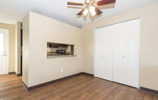 an empty living room with a ceiling fan and a closet
