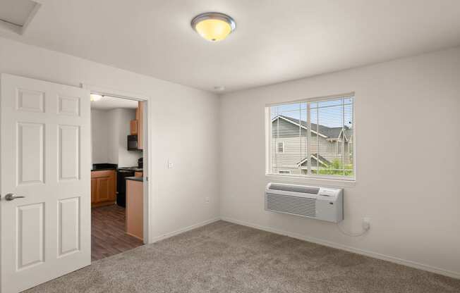 a living room with a window and a door to a kitchen