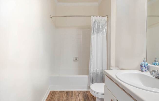 A white bathroom with a toilet, sink, and shower.