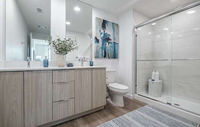 A bathroom with a toilet, sink, and a painting on the wall.