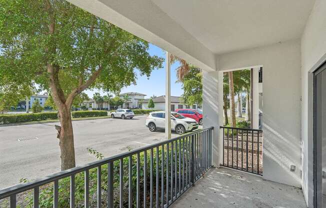 A balcony with a black railing and a tree in the foreground.