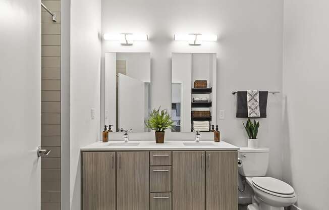 spacious bathroom with toilet sink and mirrors at the district flats apartments