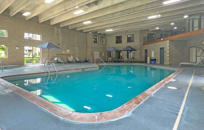 an indoor pool with tables and umbrellas