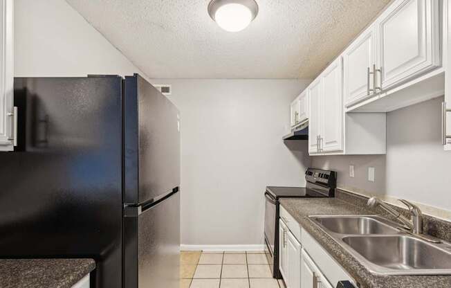 A kitchen with a black refrigerator and white cabinets.