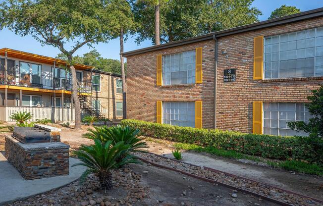 a house with bushes in front of a brick building