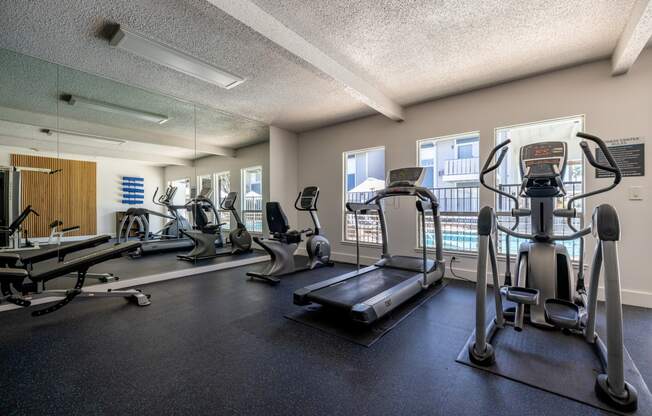 a gym with cardio machines and weights on the floor at Campbell West Apartments, California