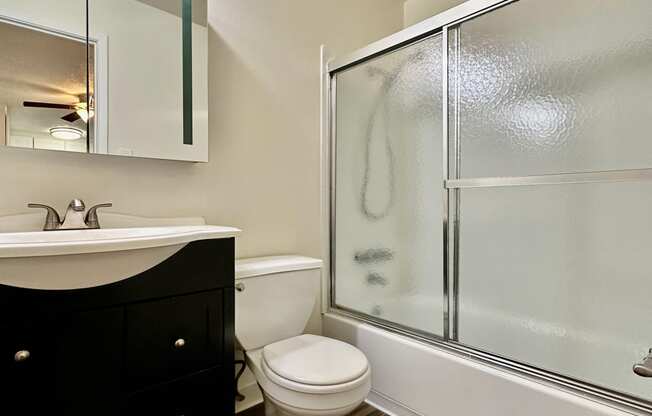 a bathroom with a toilet and a shower and a sink