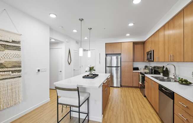 The Edge Milpitas CA a kitchen with wooden cabinetry and a large white island with a white countertop