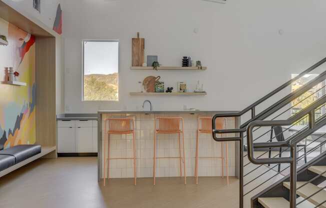 clubroom kitchen with bar stools and a staircase