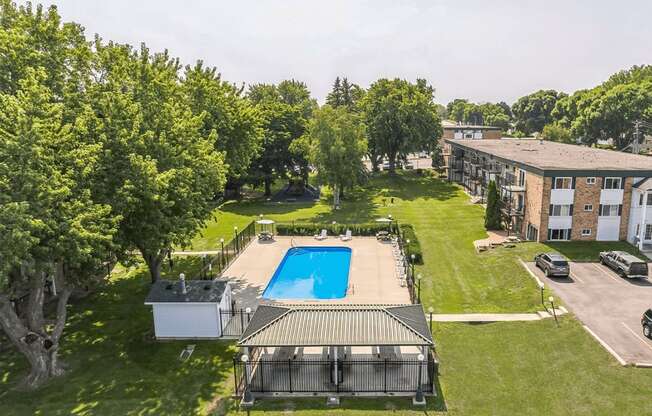 an aerial view of a swimming pool in the middle of a yard with a building