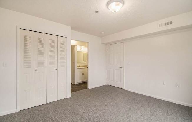 A bedroom with a carpeted floor and an ensuite and large closet at Brentwood Park Apartments, La Vista, Nebraska