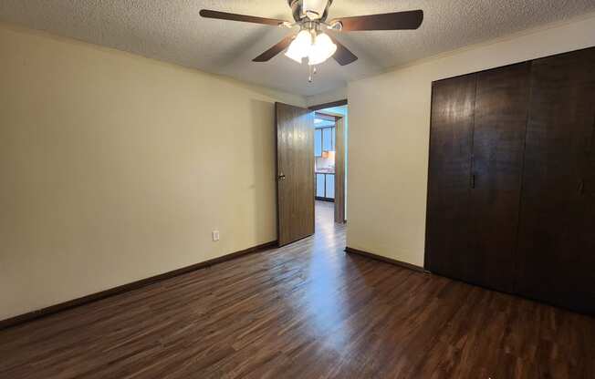 an empty living room with wood floors and a ceiling fan