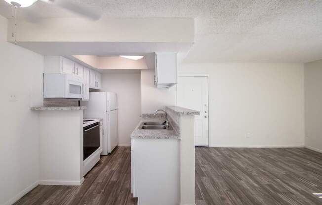 This is a photo of the living room and kitchen of the 550 square foot 1 bedroom apartment at Canyon Creek Apartments in Dallas, TX