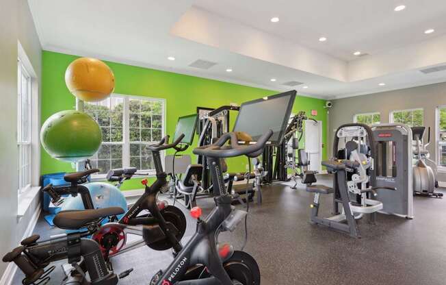 A gym with a variety of exercise equipment including treadmills, stationary bikes, and weight machines.