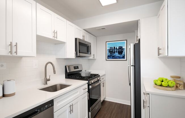 a kitchen with white cabinets and stainless steel appliances and a sink