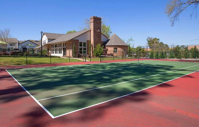 a tennis court with a house in the background