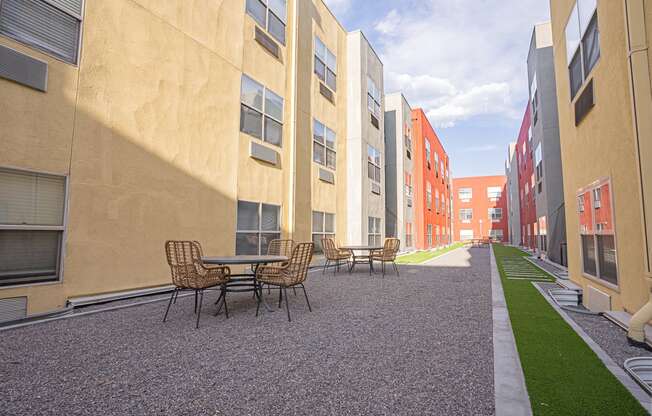 a courtyard with tables and chairs in a row of apartment buildings