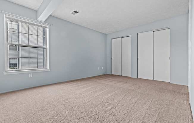 the living room of an empty home with a large window and blue walls