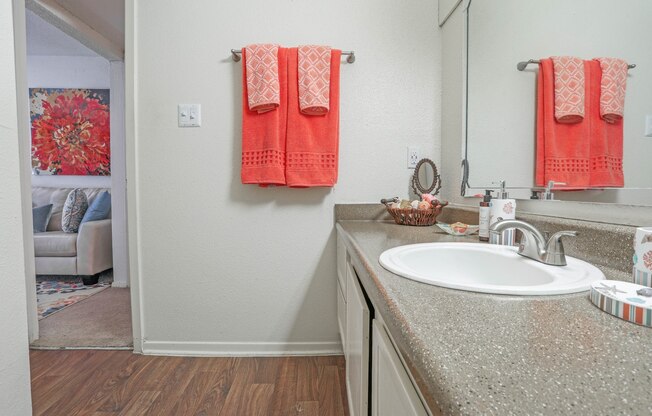 A bathroom with a spacious vanity with a white sink and orange towels at Laurel Parc apartments in Shreveport, LA.