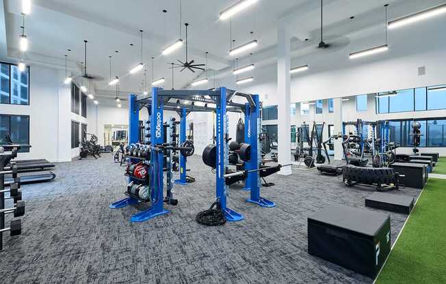 A gym with a variety of equipment including weightlifting machines and a green artificial turf area.