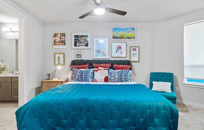 A bedroom with a blue bedspread and a ceiling fan.