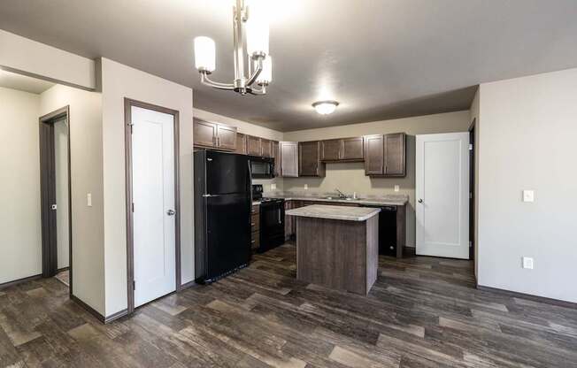 a kitchen with black appliances and wood flooring in a new home