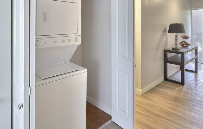 Wood floor hallway with a washer and dryer closet with open bifold doors. Extra storage space to the right of the machines. at 3030 Lake City, Seattle, 98125